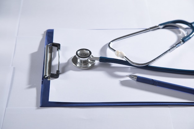 Stethoscope, pen, clipboard on white background.