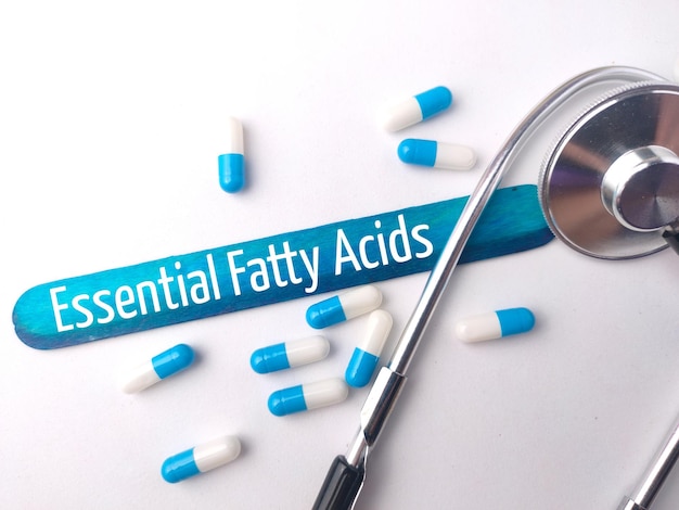 흰색 배경에 텍스트 Essentail Fatty Acids가 포함된 청진기 및 알약 캡슐