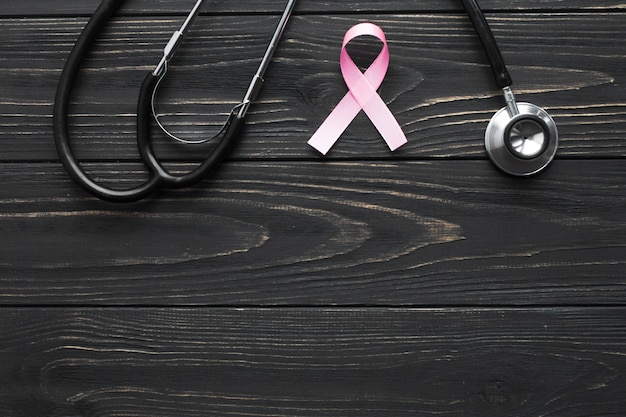 Stethoscope and pink ribbon on dark tabletop