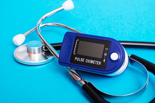 Stethoscope and pulse oximeter on blue background