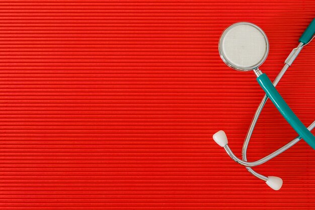 Stethoscope on a red background top view with free space