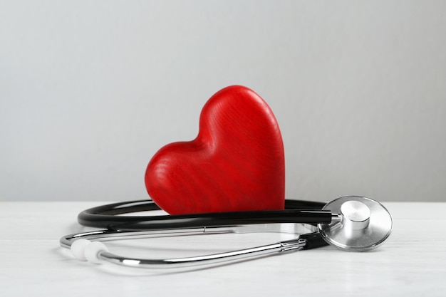 Stethoscope and red heart on white wooden table Cardiology concept