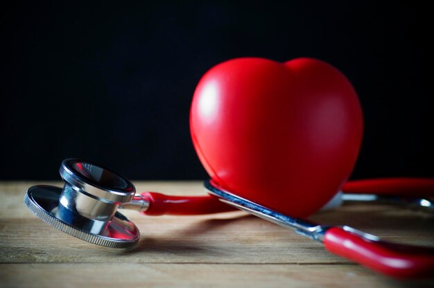 Stethoscope and red heart on wood background