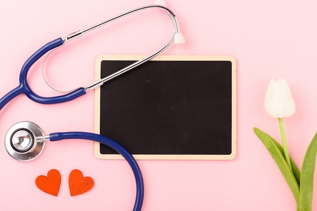 Stethoscope, red hearts, blackboard and tulip flower