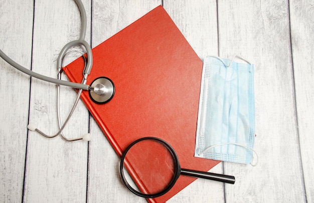 Stetoscopio e blocco note rosso su sfondo bianco vista dall'alto