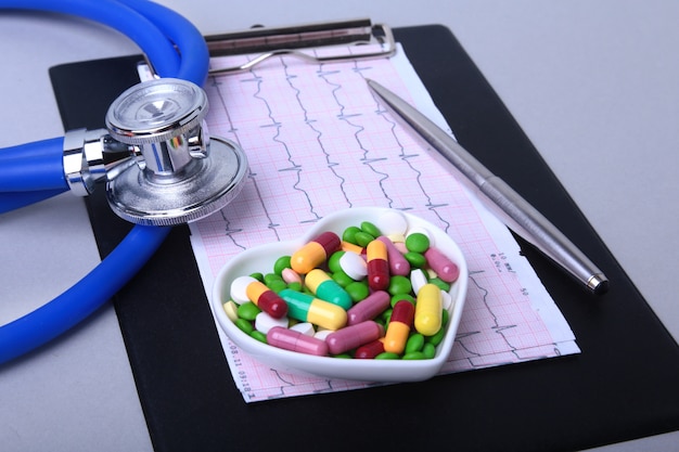 Stetoscopio, prescrizione rx e assortimento di pillole colorate e capsule sul piatto.