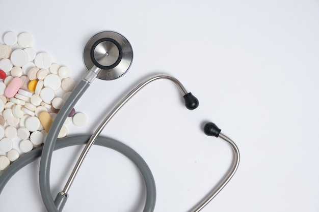 Stethoscope and scattered expired pills on white background