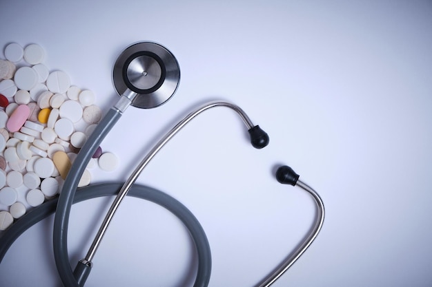 Stethoscope and scattered expired pills on white background