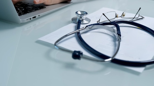 A stethoscope sits on top of a laptop next to a stethoscope.