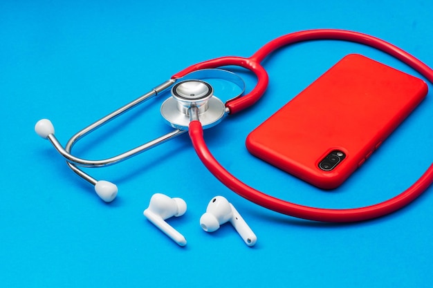 Stethoscope a smartphone next to wireless headphones telehealth concept