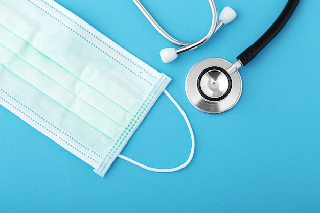 Stethoscope and surgical mask on blue background