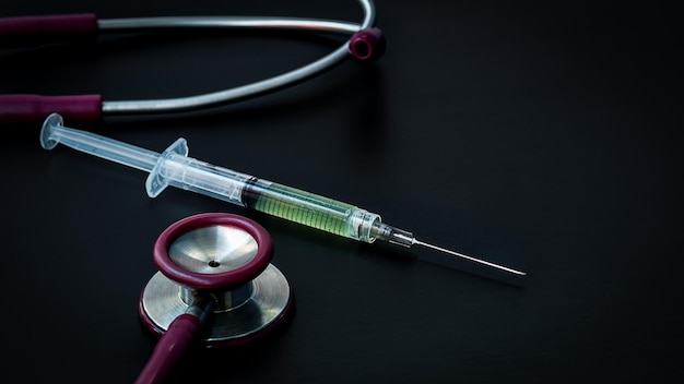 stethoscope and syringe on black background with copy space