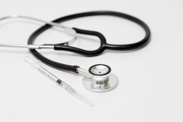 stethoscope and syringe on table