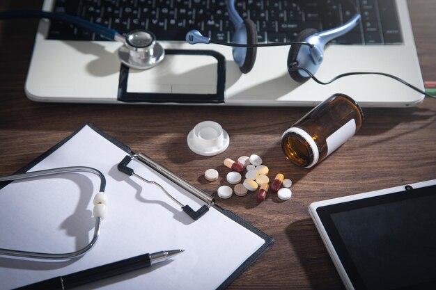 Stethoscope tablet clipboard headset and pills on the desk