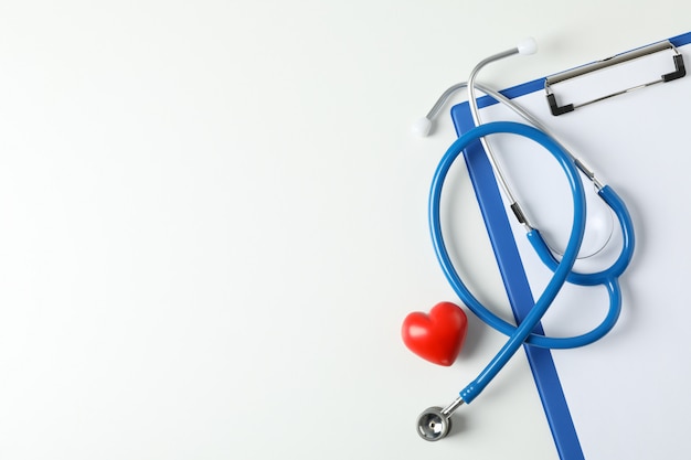 Stethoscope, tablet and heart on white background, space for text