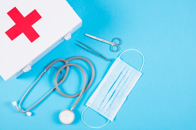 Stetoscopio e kit di pronto soccorso bianco e attrezzatura medica su fondo blu in bianco
