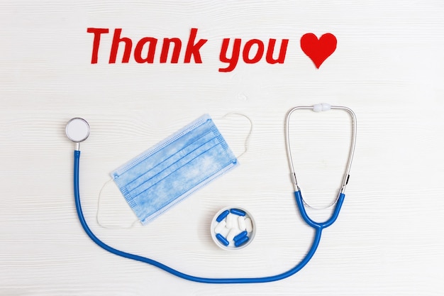 Photo stethoscope with blue colored pills red heart shape and thank you text