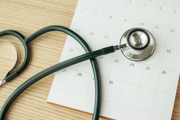 Stethoscope with calendar page date on wood table background doctor appointment medical concept