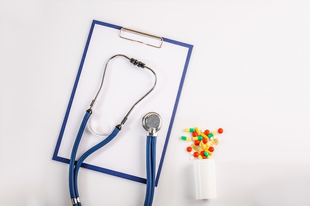 Stethoscope with clipboard and pills, top view