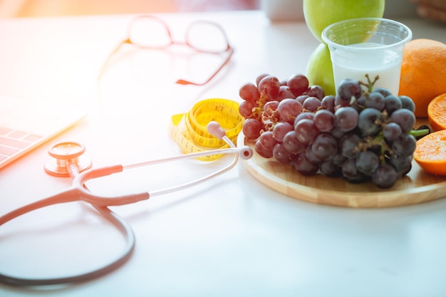 Lo stetoscopio con frutta e latte per il medico consiglia di mangiare un concetto di cibo sano