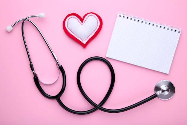 Stethoscope with notebook on pink 