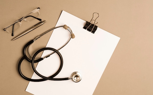 stethoscope with notepad, glasses and pen, gray background with copy space.