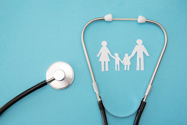 Stethoscope with paper cutout family on blue background family healthcare concept