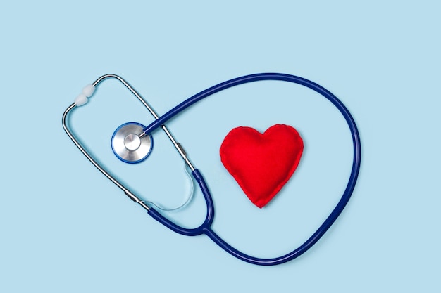 A stethoscope with a red heart on a light blue background in a top view