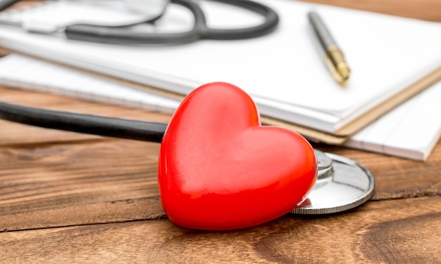 Stethoscope with red heart and notepad on the table