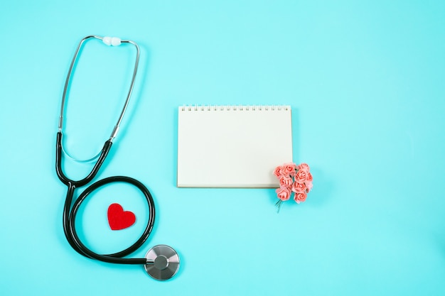 Photo stethoscope with red heart, small flowers and notebook