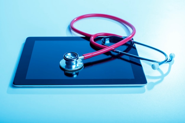 Stethoscope with tablet computer on blue background