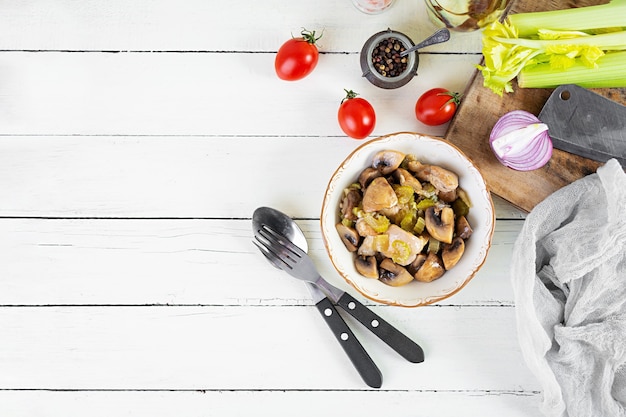 Stew chicken thighs with mushrooms, celery, onion and pepper. Stir fry chicken on wooden background