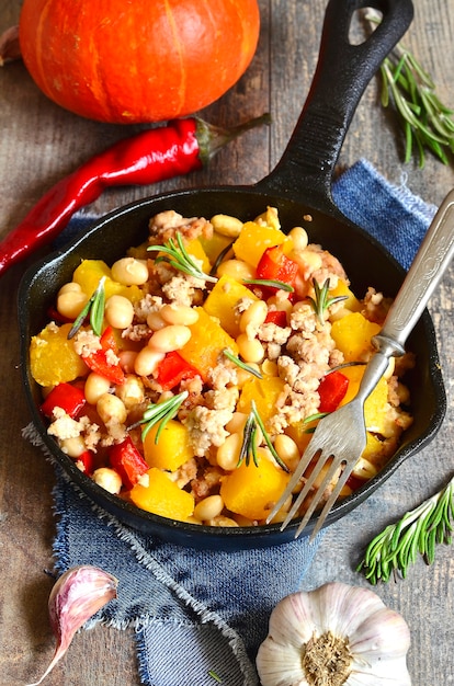 Stew from pumpkin beans and ground meat with rosemary in a pan