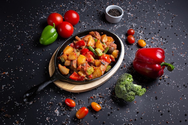 Stew served in restaurant, beautifully decorated, on black, with tomatoes, red green peppers and broccoli