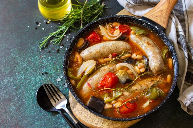 Stufato di salsicce affumicate con verdure di fagioli e salsa di pomodoro in padella copia spazio