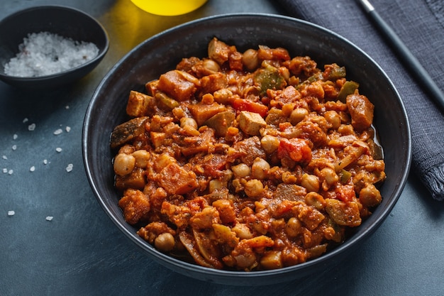 Stew vegetables ragout vegan with tofu served in bowl on dark.