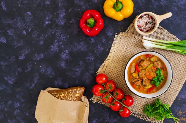 Stew with meat and vegetables in tomato sauce on dark