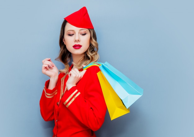 stewardess draagt in rood uniform met boodschappentassen.