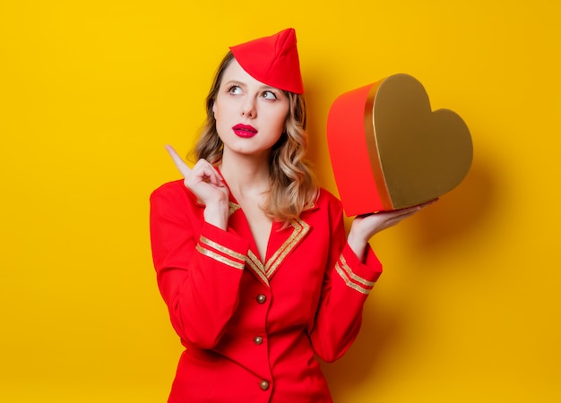 Foto stewardess dragen in rode uniform met hart vorm vakantie gfit box