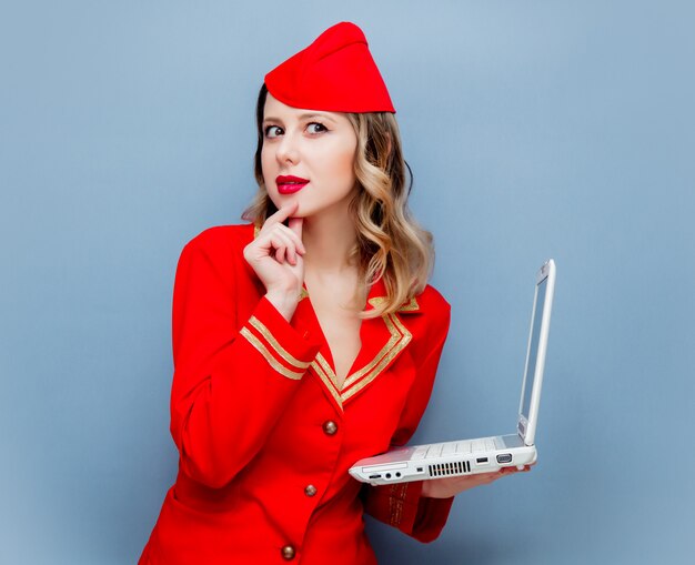 stewardess dragen in rode uniform met laptopcomputer