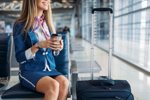 Stewardess met koffie op stoel in wachtruimte