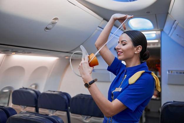 Stewardess toont veiligheidsregels voor het vliegen in de avondvliegtuigsalon