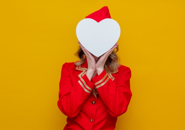 Фото Стюардесса в красной форме с праздничной коробкой в форме сердца