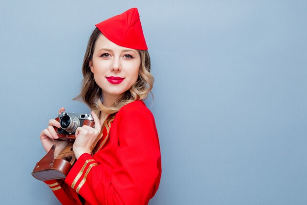 Hostess che indossa in uniforme rossa con macchina fotografica d'epoca