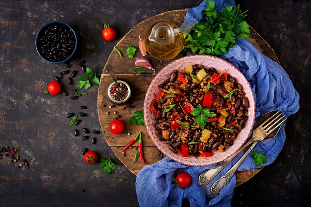 Stewed black beans with sweet peppers and tomatoes with spicy sauce in a pan. Flay lay. To