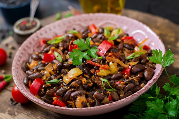 Stewed black beans with sweet peppers and tomatoes with spicy sauce in a pan. 