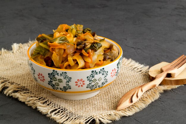 Stewed cabbage in bowl on grey background.