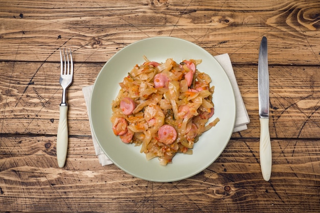 Foto cavolo stufato con salsicce in un piatto sul tavolo.