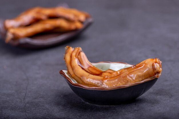 Photo the stewed duck claws in the container are in a dark background