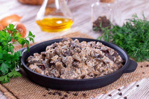 Stewed eggplant with vegetables and sour cream in a pan on a wooden table